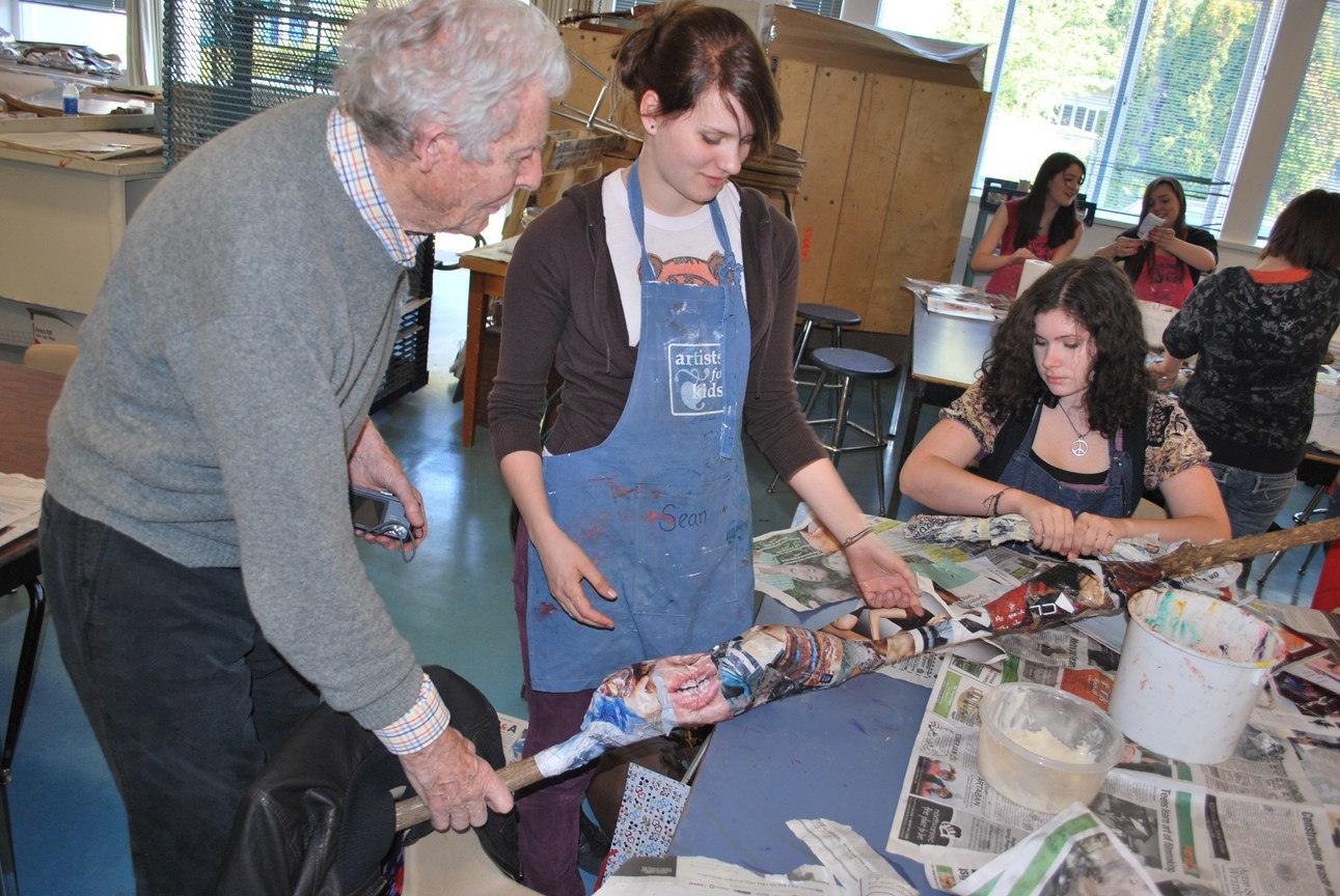 Gordon Smith in a classroom, with students at a table, listening